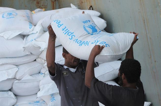 Workers unload bags of food from a UN's World Food Programme ship docked in Yemen's port city of Aden