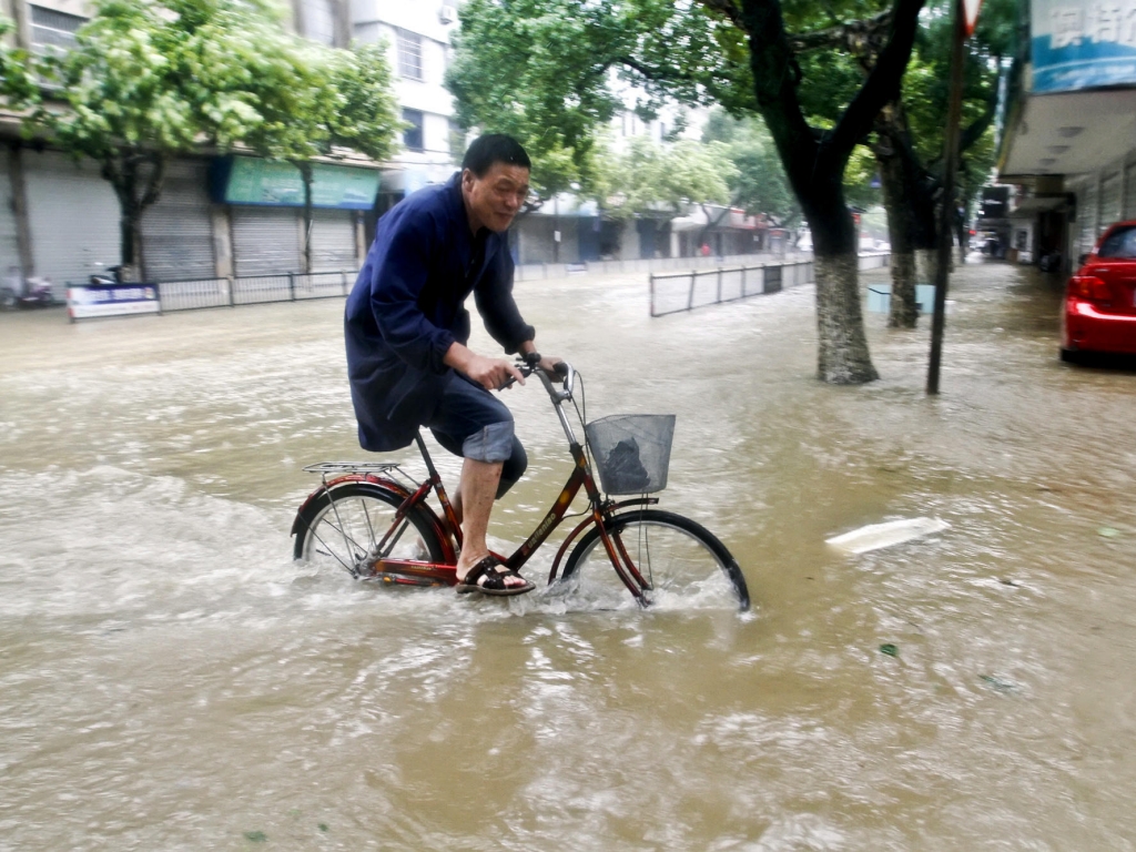 A resident rides a bicycle on a road submerged by water in Xiangshan county east China's Zhejiang Province on Saturday after Typhoon Chan-hom hit the Chinese coast south of Shanghai forcing 1.1 million people to evacuate