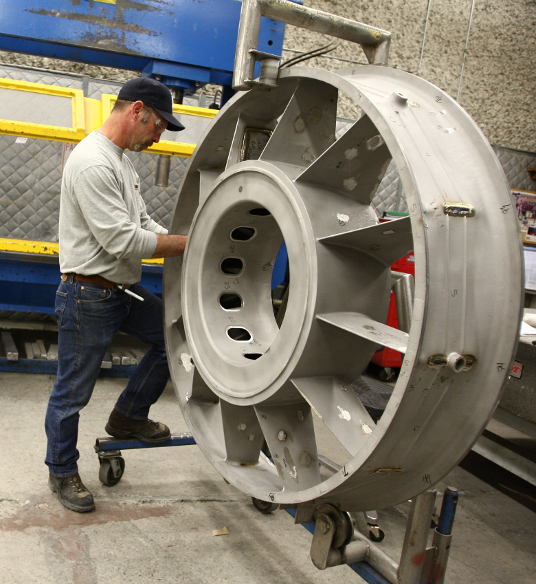 A Precision Castparts worker in Portland inspects a part that will go on an aircraft engine