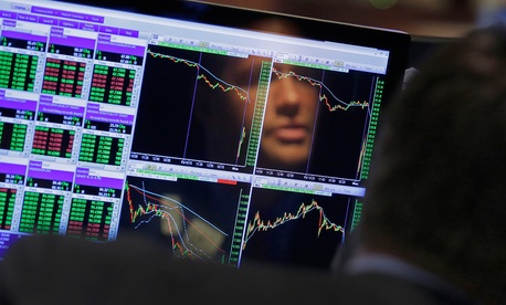 A Wall St. worker is reflected in his laptop screen Monday