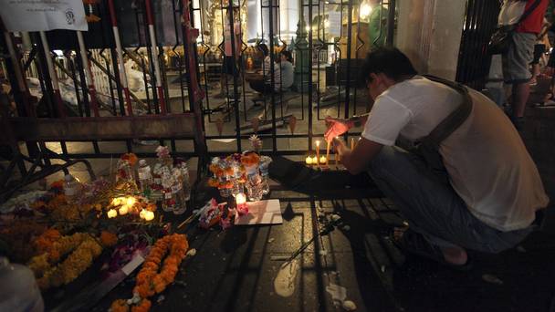 A man lights candles near Erawan Shrine in Bangkok