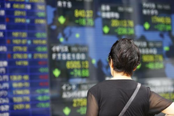 A woman looks at an electronic stock indicator