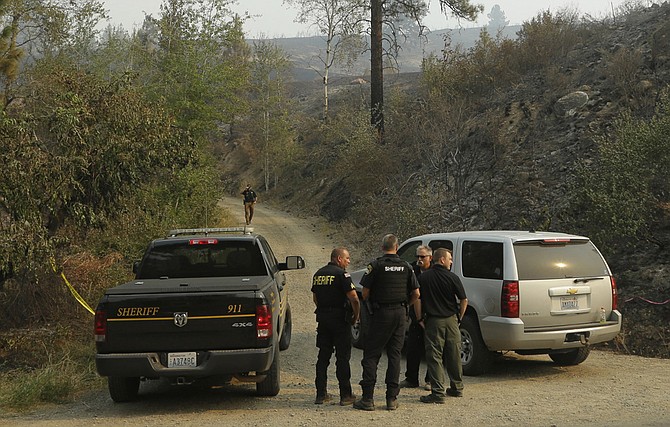 Okanogan County Sheriff's deputies guard the entrance to Woods Canyon Road near Twisp Wash. Three firefighters were killed after their engine rushed up a steep gravel road and crashed down a 40-foot embankment near the mountain town of Twisp. Before