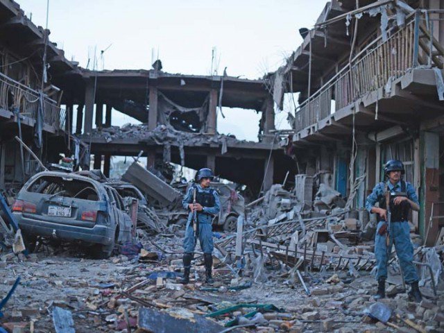 Afghan policemen stand guard at a market destroyed by a powerful truck bomb in Kabul