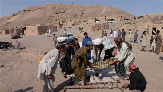 Afghan men carry the body of a victim after a series of explosions at a gas storage facility on the edge of the western city of Herat