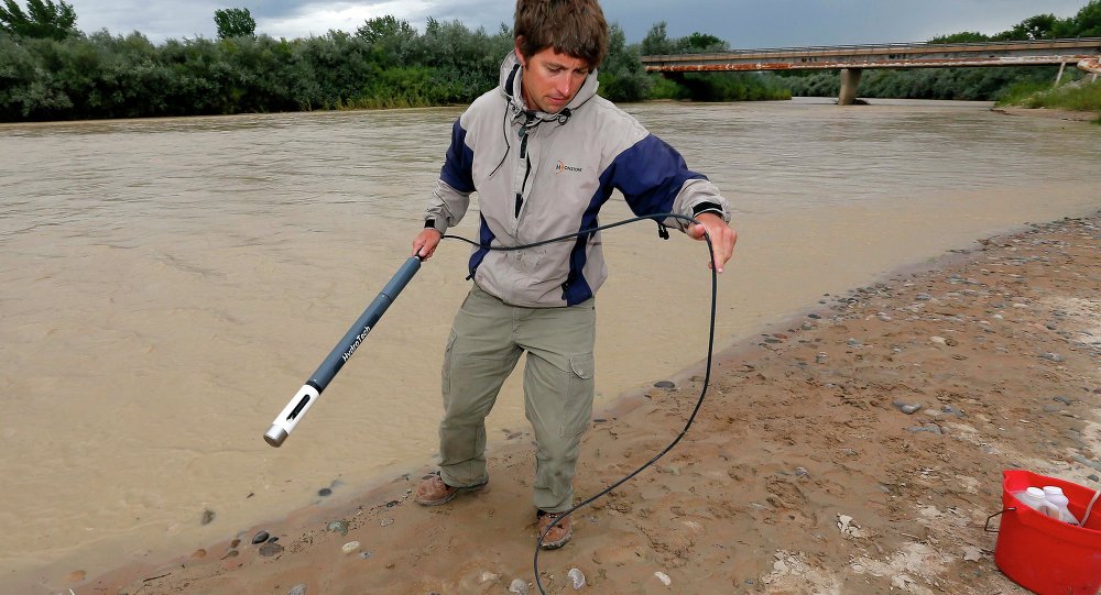 An official with the Utah Department of Environmental Quality takes a pH level reading from a probe in the San Juan River in Utah