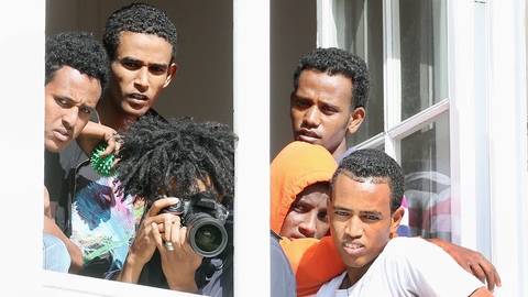 Asylum seekers watch as Chancellor Angela Merkel visits a Berlin refuge yesterday