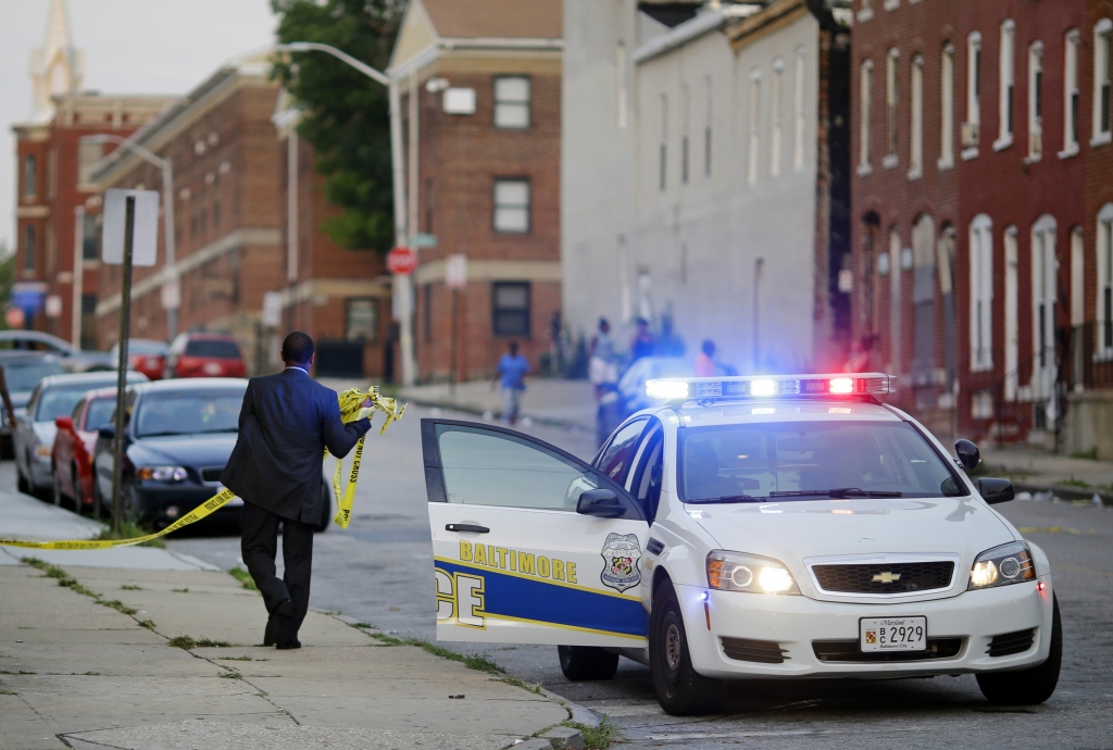 A member of the Baltimore Police Department removes crime scene tape from a corner where a victim of a shooting was discovered in Baltimore