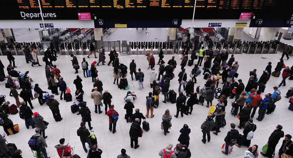 People wait with their luggage by the departure boards in Waterloo train station in central London