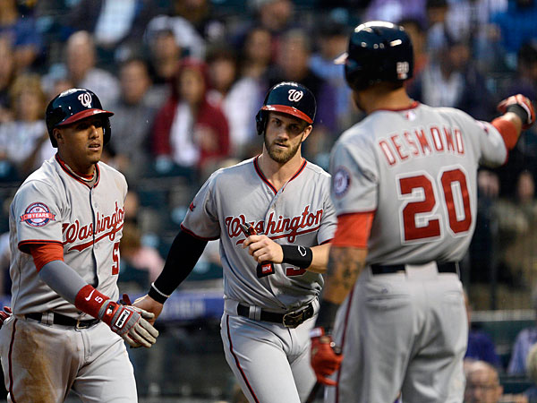 Washington Nationals third baseman Yunel Escobar is congratulated by right fielder Bryce Harper and shortstop Ian Desmond after a two run home run in the first inning against the Colorado Rockies at Coors Field