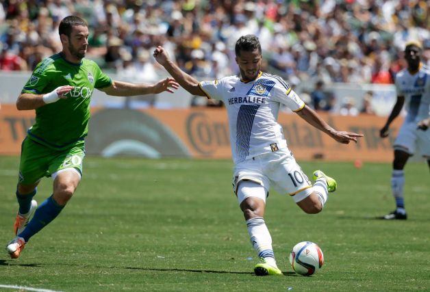 Los Angeles Galaxy's Giovani Dos Santos right shoots under pressure by Seattle Sounders’ Zach Scott during the first half of an MLS soccer match Sunday Aug. 9 2015 in Carson Calif