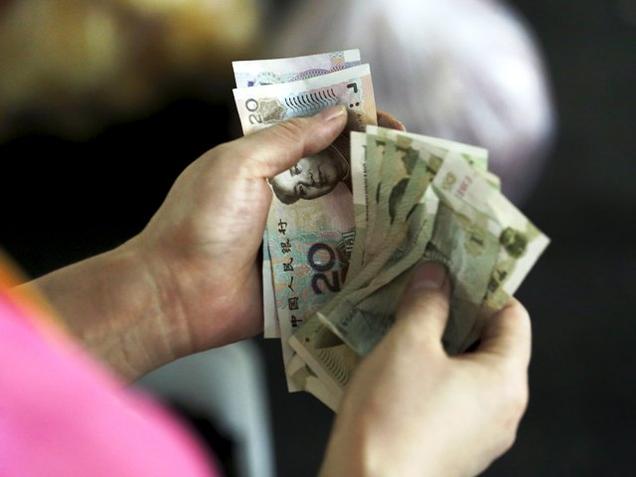 A customer counts Chinese Yuan notes at a market in Beijing