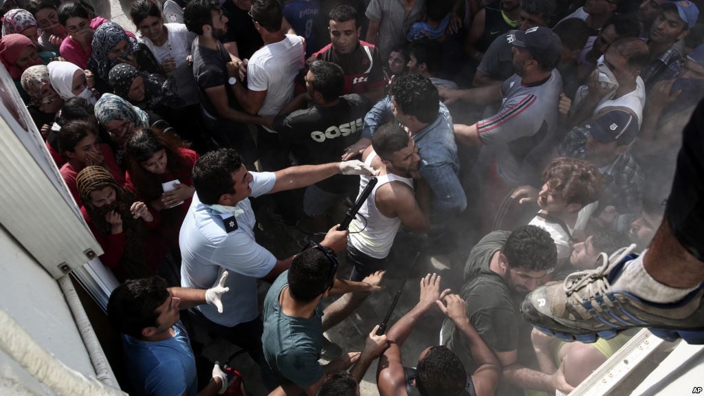 A policeman hits a migrant as police try to disperse hundreds of migrants during a registration procedure that was taking place at the stadium of Kos town on the southeastern island of Kos Greece Aug. 11 2015