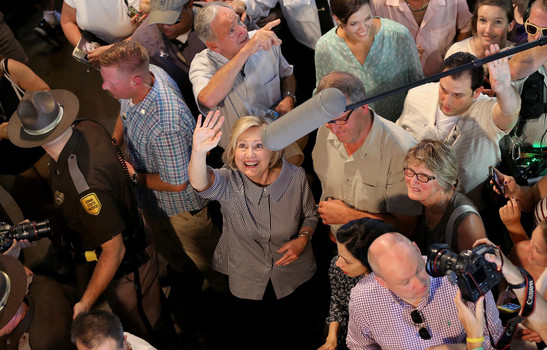 Democratic presidential candidate Hillary Clinton eats a pork chop on a stick and carries a lemonade while greeting fairgoers at the Iowa State Fair