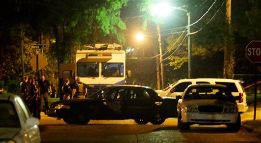 Law enforcement officials surround the scene where a Shreveport police officer was shot Wednesday Aug. 5 2015 in Shreveport La. Police in northwest Louisiana say an officer has died after being shot while on duty and a manhunt for a suspect is under