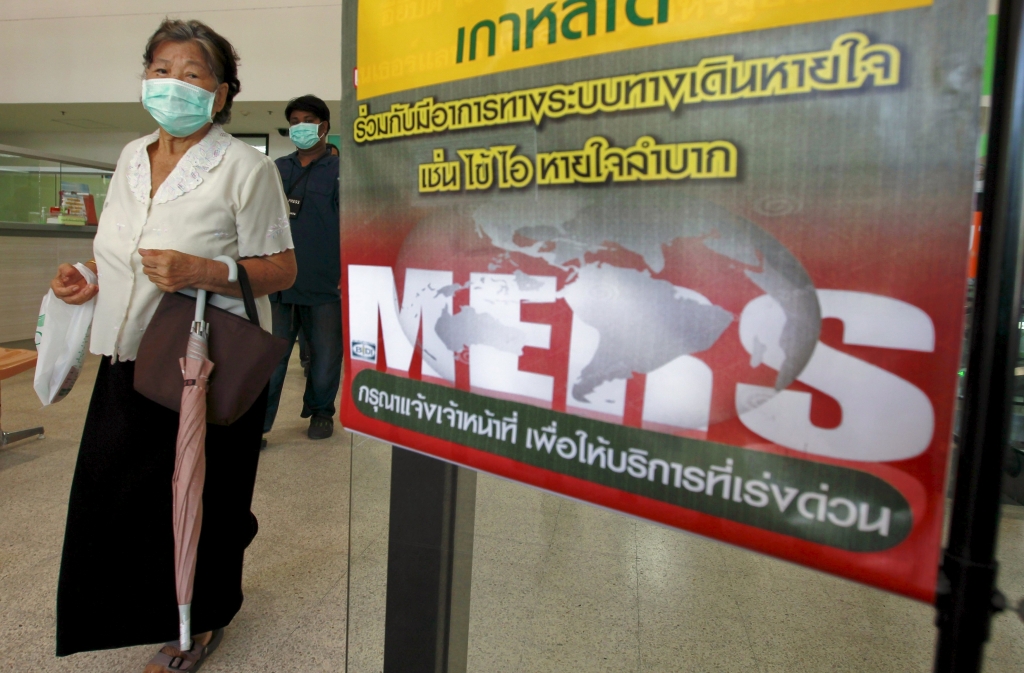 A woman wearing a mask walks past an information banner on Middle East Respiratory Syndrome at the entrance of Bamrasnaradura Infectious Diseases Institute at a hospital in Nonthaburi province on the outskirts of Bangkok Thailand