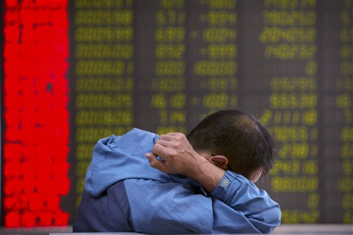 A Chinese investor monitors stock prices at a brokerage house in Beijing Tuesday Aug. 25 2015. China's main stock market index has fallen for a fourth day plunging 7.6 percent to an eight-month low