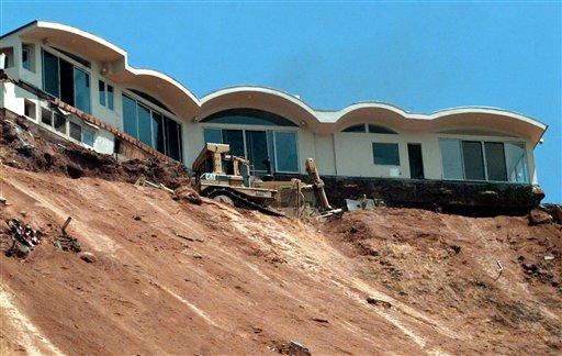 Caltrans bulldozer terraces a sliding hillside below the condemned home above Pacific Coast Highway near Las Flores Canyon Road in Malibu Calif. The home and at least one other at the top of the slide was schedu