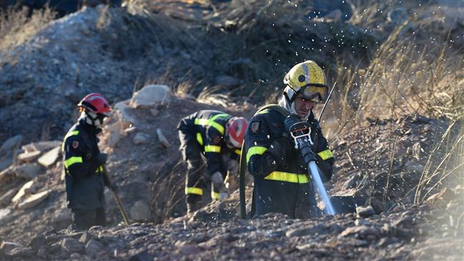 Firefighters douse an area near a campsite following a wildfire in Bagnols-en Foret in southern France