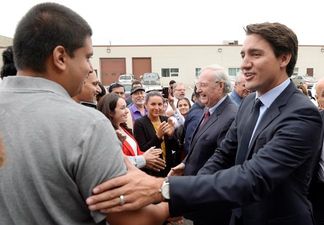 Liberal Leader Justin Trudeau right and former prime minister Paul Martin centre greet supporters during a campaign stop in Toronto on Tuesday