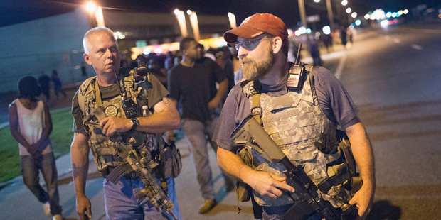 Oath Keepers carrying rifles'patrol the streets as demonstrators mark the first anniversary of the shooting of Michael Brown