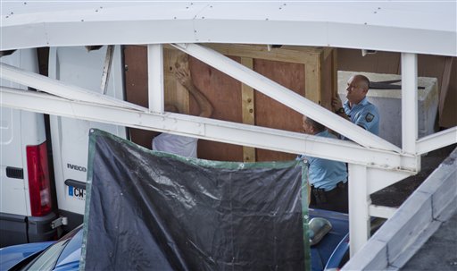 Members of the French gendarmerie carry a wooden box containing the wing part that was washed up on a beach as they maneuver it into a van ready to be put onto a flight to France at the Roland Garros Airport in Sainte-Marie on the north coast of the In