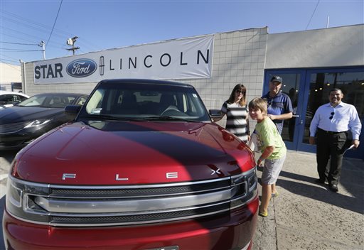 Robert Schemer his wife Kelly and their son Graham 9 pose next to their newly purchased pre-owned 2013 Ford Flex Limited at the Star Ford Lincoln dealership in Glendale Calif. At right is sales consultant Alla