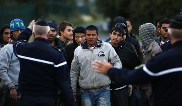 French police stop migrants on their way to catch a train to reach England in Calais France