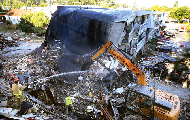 Firefighters hose down the debris field from the collapsed east side of the Bremerton Motel 6 Wednesday morning Aug. 19 2015. A gas explosion leveled the building Tuesday evening. The blast critically injured a gas company worker minutes after the acti