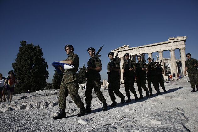 Greek army soldiers perform a ceremonial march past the Parthenon temple before raising the national flag on Acropolis Hill in Athens Greece on Aug. 19. 2015