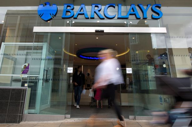 Pedestrians pass a Barclays bank