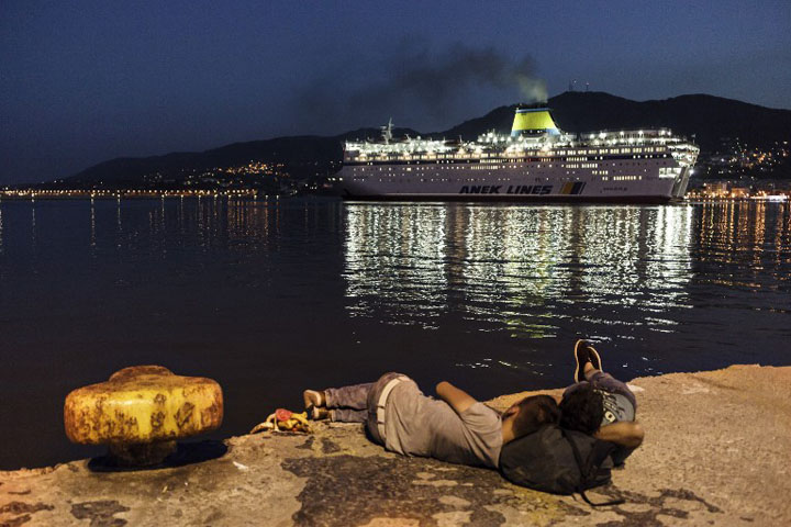 TOPSHOTS Migrants sleep on the dock as the Eleftherios Venizelos ferry arrives at the port of Mytilene on Lesbos Island to transport Syrian refugees from the island to mainland Greece