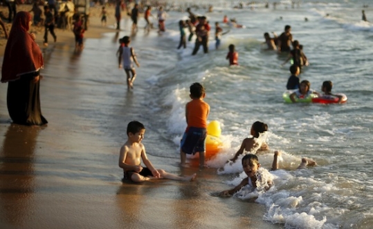 Palestinian children swim in the Mediterranean Sea as they enjoy the warm weather in the northern Gaza Strip