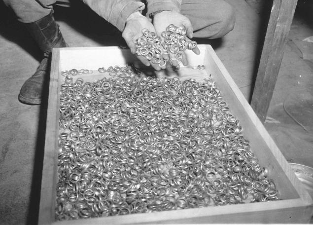 A US soldier inspects thousands of gold wedding bands taken from Jews by the Nazis and stashed in the Heilbron Salt Mines