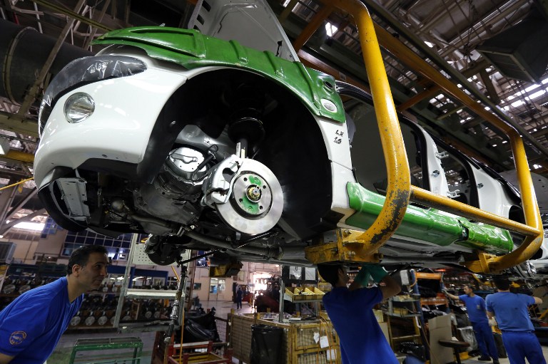 Iranian men work on a Peugeot 206 at the Iran Khodro auto plant west of Tehran