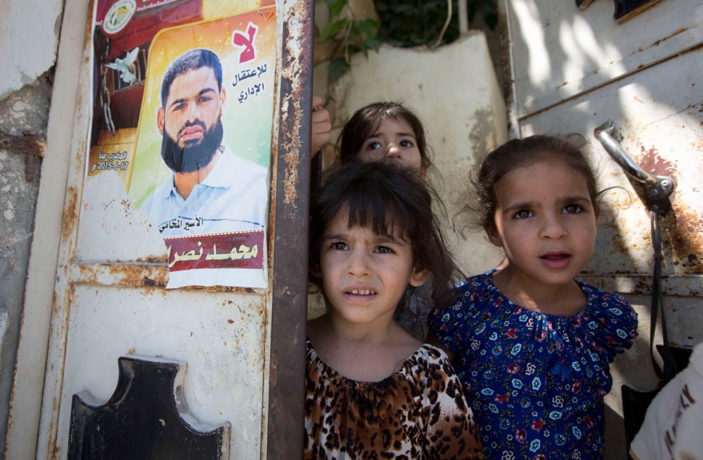 Palestinian girls from left Ghofran Lane and Mary stand next to a poster showing their uncle Mohammed Allan at the family house in the village of Einabus near the West Bank city of Nablus