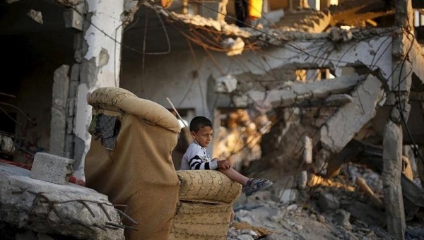 A Palestinian boy sits on a sofa outside his family house that witnesses said was destroyed during the 50-day war last summer in the east of Gaza City