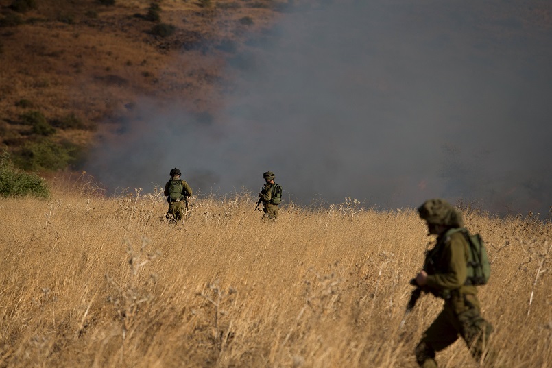 Israeli soldiers patrol next to smoke from a fire caused by a rocket attack in northern Israel near the Lebanese border. Rockets that struck a northern Israeli village near the Lebanese border causing no casualties were launched from the Syrian Golan H