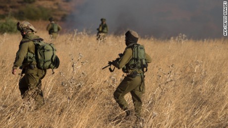 Israeli soldiers on Thursday inspect a field where rockets landed