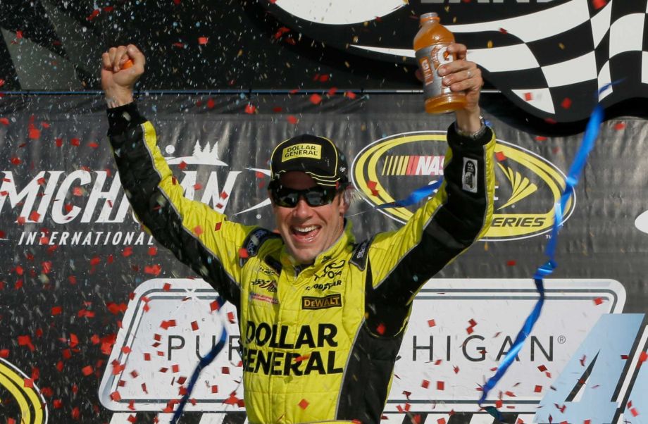 Matt Kenseth raises his arms in victory lane after winning the NASCAR Sprint Cup series auto race at Michigan International Speedway Sunday Aug. 16 2015 in Brooklyn Mich