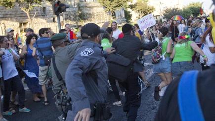 Security forces reach for a knife-wielding ultra Orthodox Jew attacking people with a knife during a Gay Pride parade in central Jerusalem