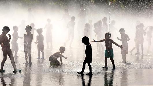 Children cool off as they play under a fountain