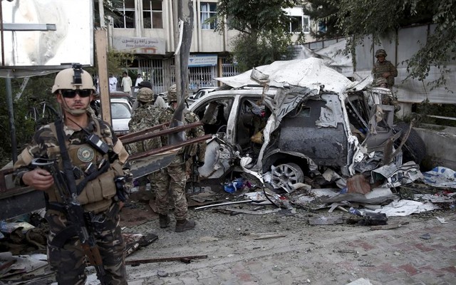 Afghan security personnel keeps watch next to a damaged car belonging to foreigners after a bomb blast in Kabul Afghanistan