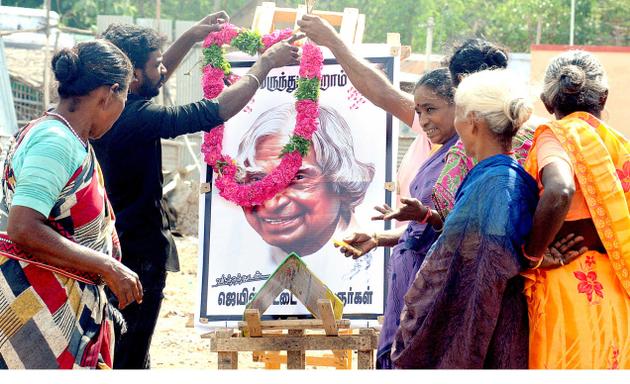 People pay floral tributes to the portrait of the former president A.P.J. Abdul Kalam. At right students of the K.A.P. Viswanatham Government Medical College hold a candle light vigil in Tiruchi on Thursday