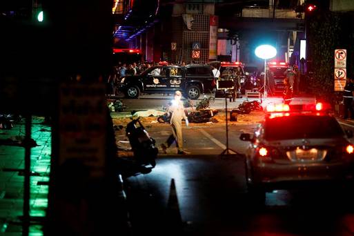 The body of a victim covered with a sheet is seen as security forces and emergency workers gather at the scene of the blast in central Bangkok