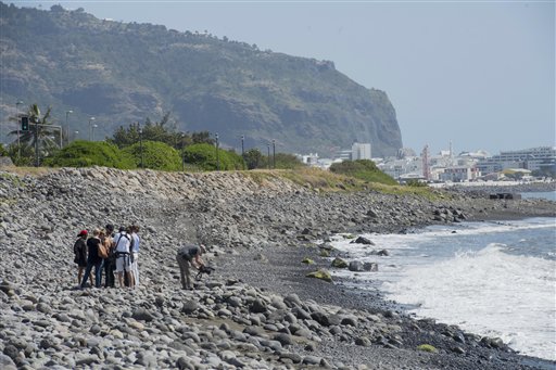 Workers search the beach for possible additional airplane debris near the shore where an airplane wing part was washed up in the early morning near to Saint Denis on the north coast of the Indian Ocean island of Reunion Sunday Aug. 2 2015. (AP