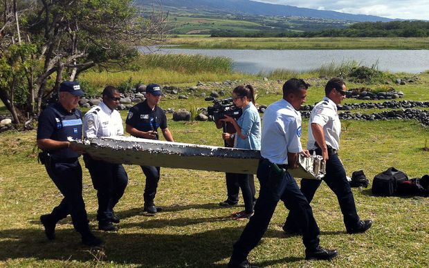 Police carry a piece of debris from an unidentified aircraft found in the coastal area of Saint Andre de la Reunion in the east of the French Indian Ocean island of La Reunion