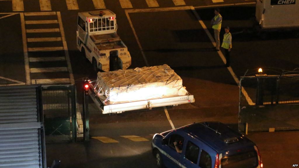 Police officers escort an airport vehicle transporting what is believed to be debris from a Boeing 777 plane that washed up on Reunion Island at Roland Garros airport in Saint-Marie Reunion Island