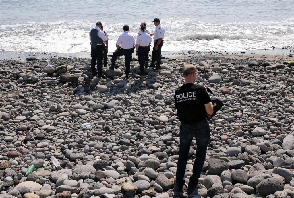 Image Police officers inspect metallic debris found on a beach on Reunion Island