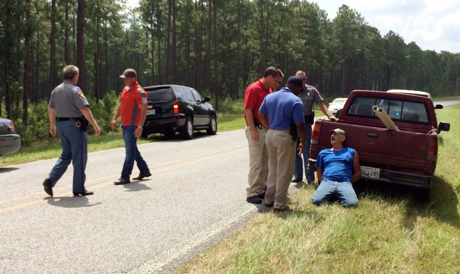 Mississippi Bureau of Investigation agents and state troopers detain a person of interest right after shots were reportedly fired a second consecutive day near Camp Shelby a military training facility near Hattiesburg Miss. Wednesday Aug. 5 2015. T